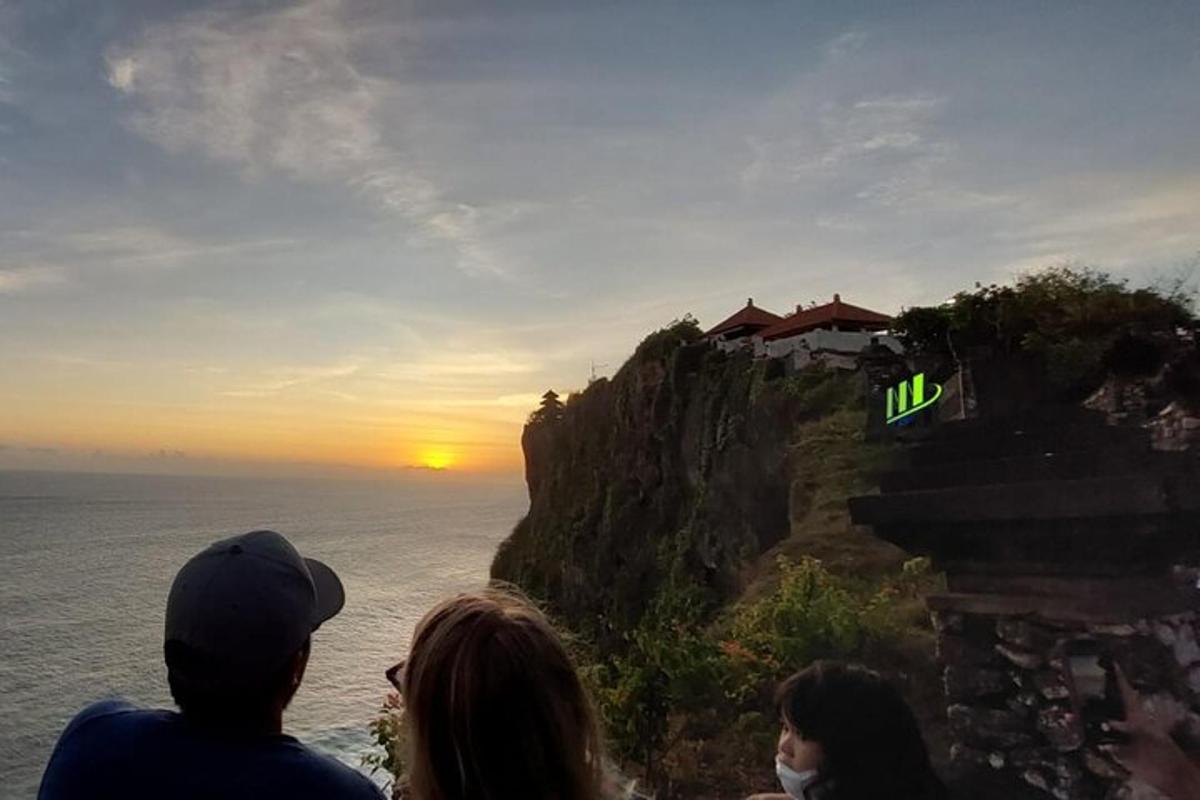 Un grupo de personas mirando la puesta de sol en un acantilado
