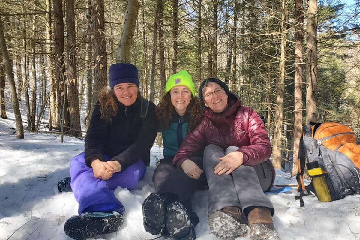 three people sitting in the snow in the woods