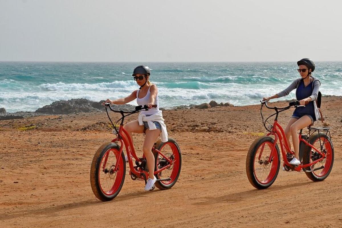 two people riding bikes on the beach