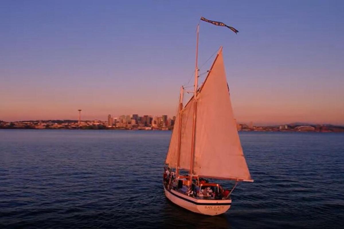 a sail boat in the water with a city in the background