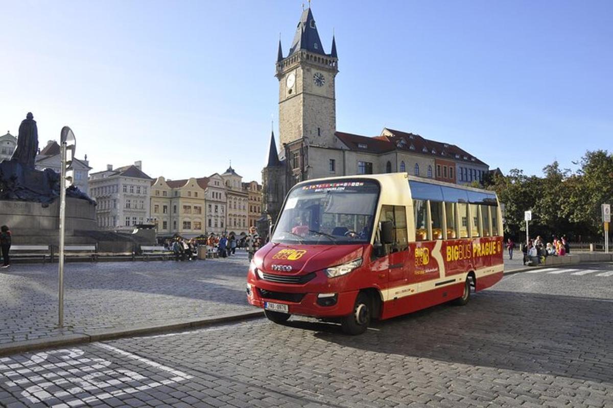 un piccolo autobus che percorre una strada con una torre dell'orologio