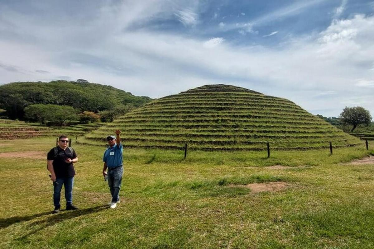 due uomini in piedi in un campo di fronte a una grande collina