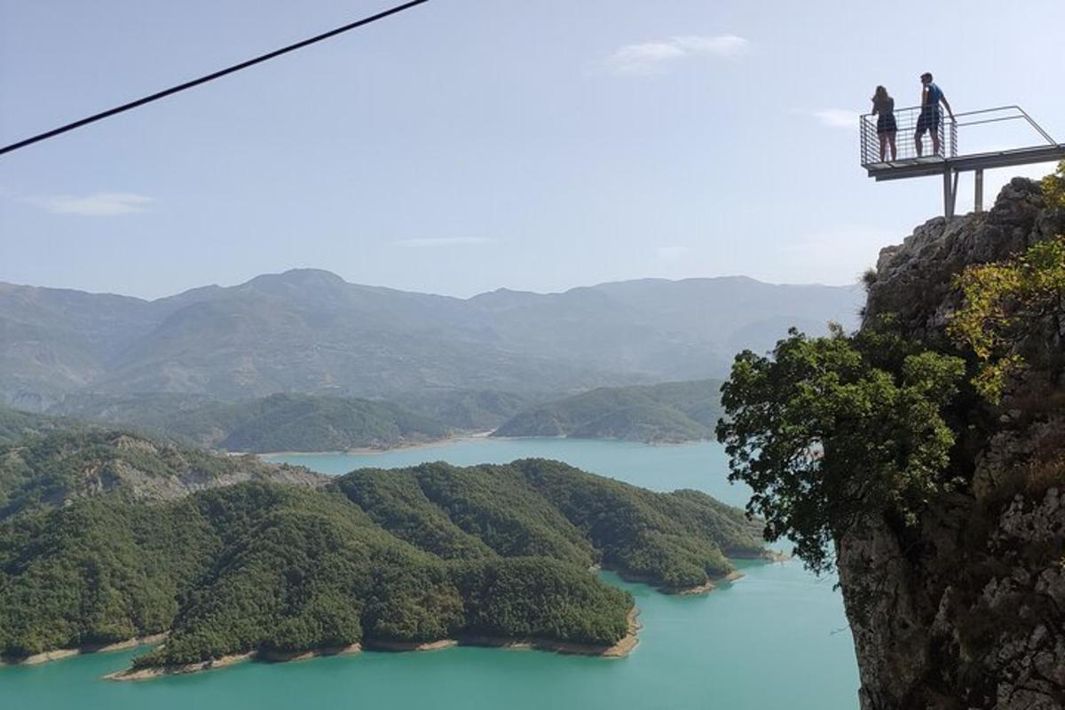 două persoane stând pe un pod suspendat peste un lac