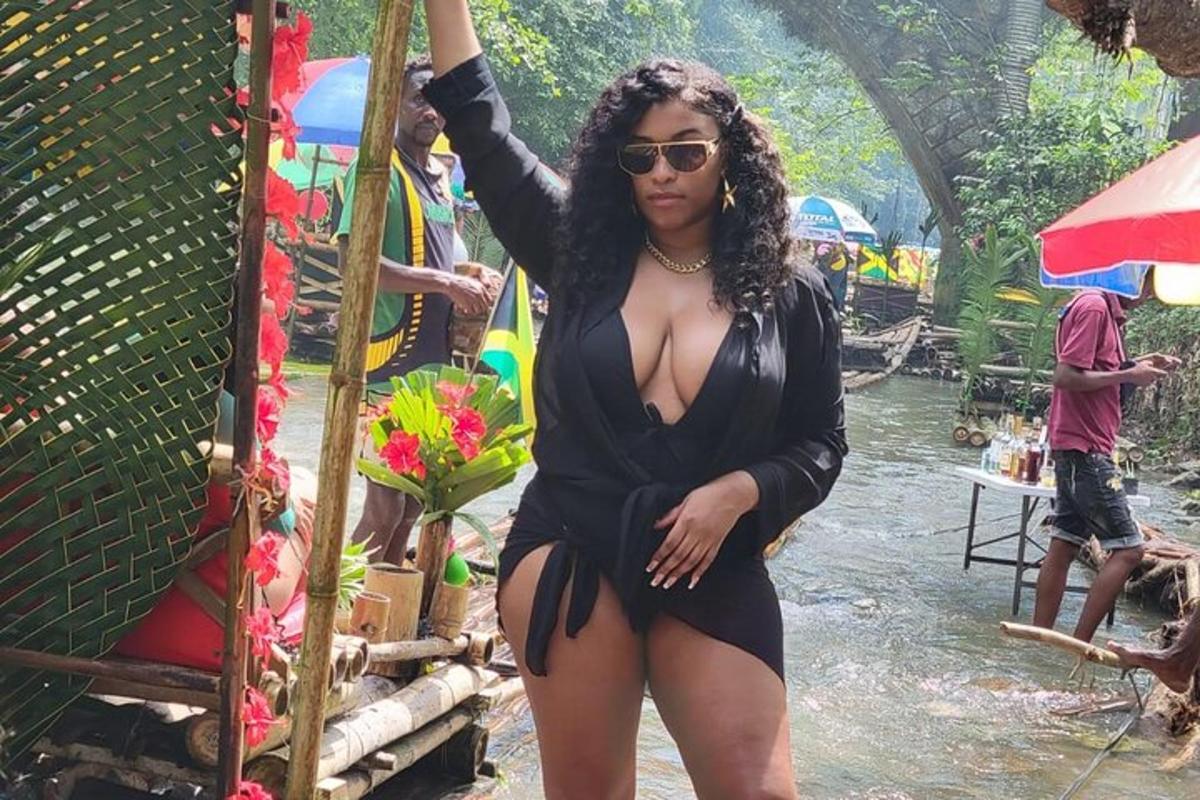 uma mulher de maiô preto parada ao lado de um rio