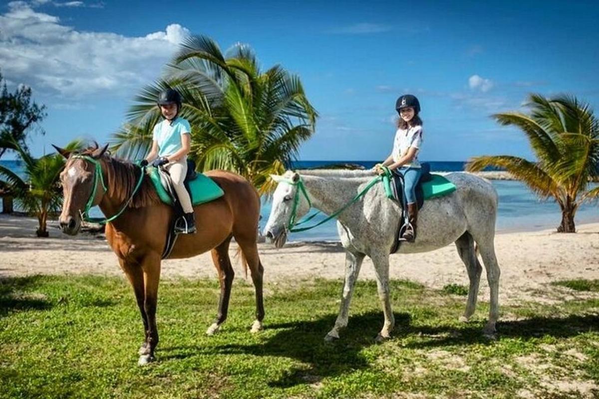 two people riding on horses on the beach