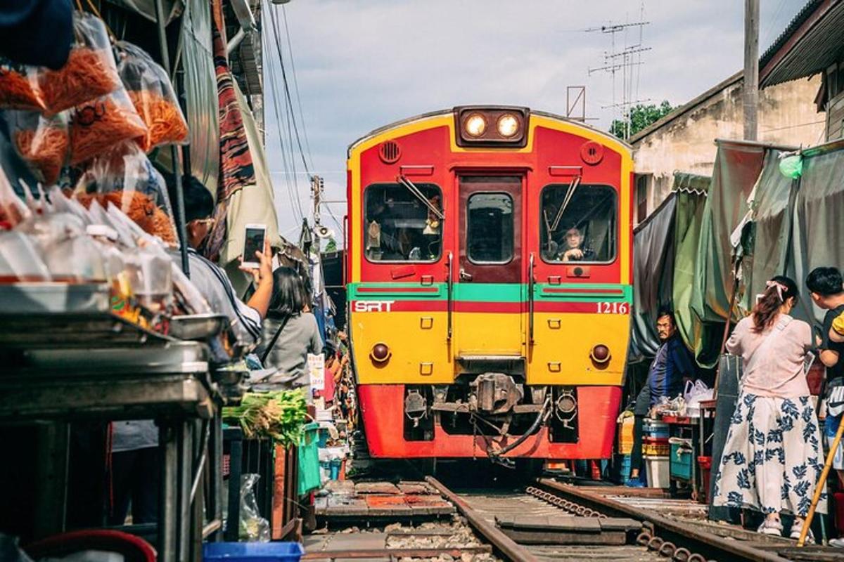 a red and yellow train traveling through a market