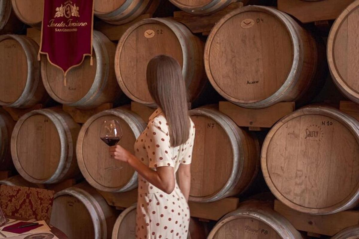 Una mujer parada frente a un montón de barriles de vino.