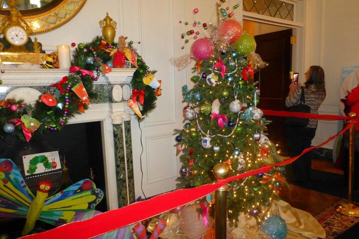 a woman standing in a living room with christmas trees