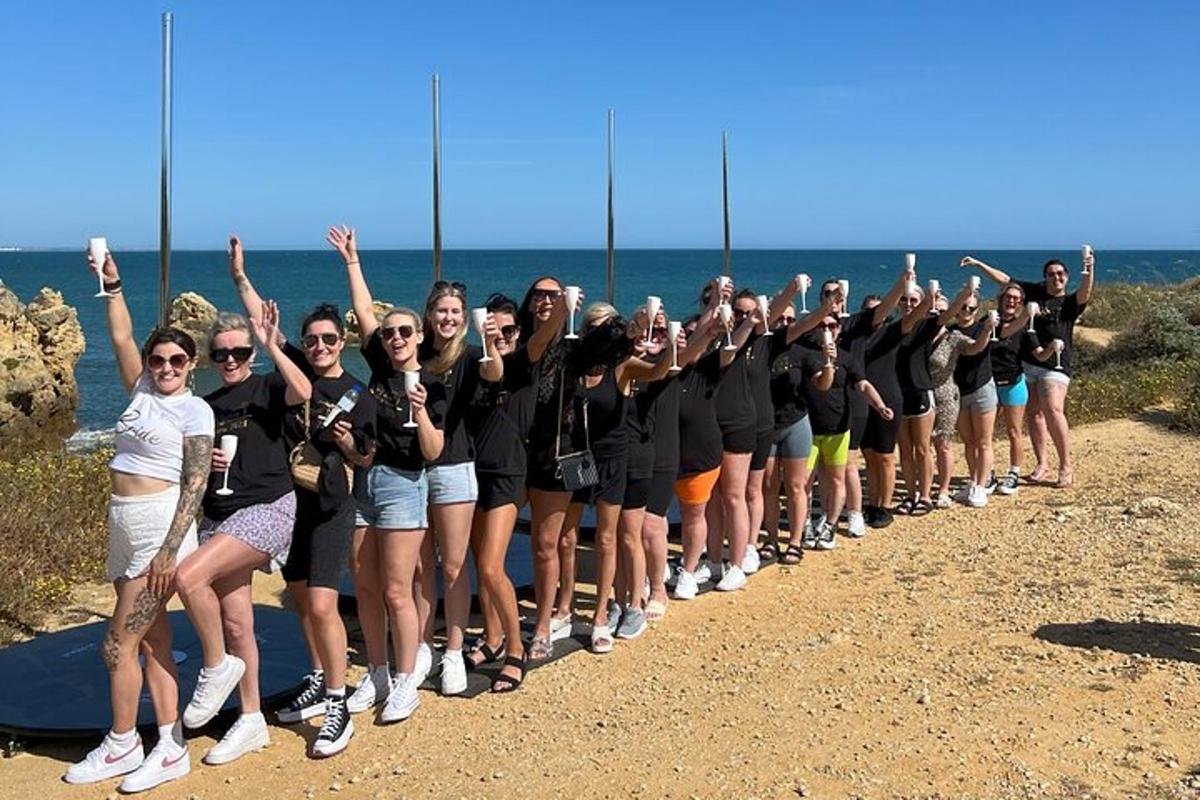 un grup de dones dretes a la platja amb les mans enlaire