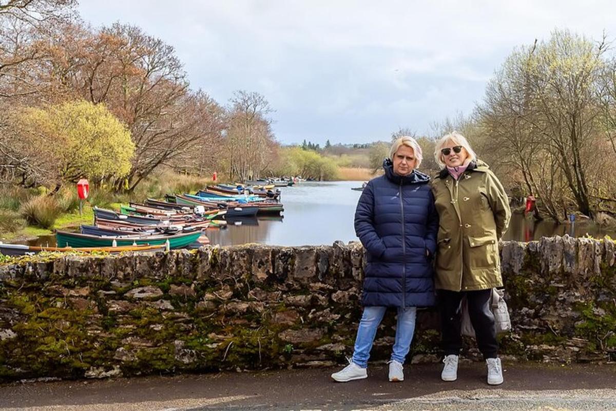Dos mujeres de pie junto a un muro de piedra junto a un río.