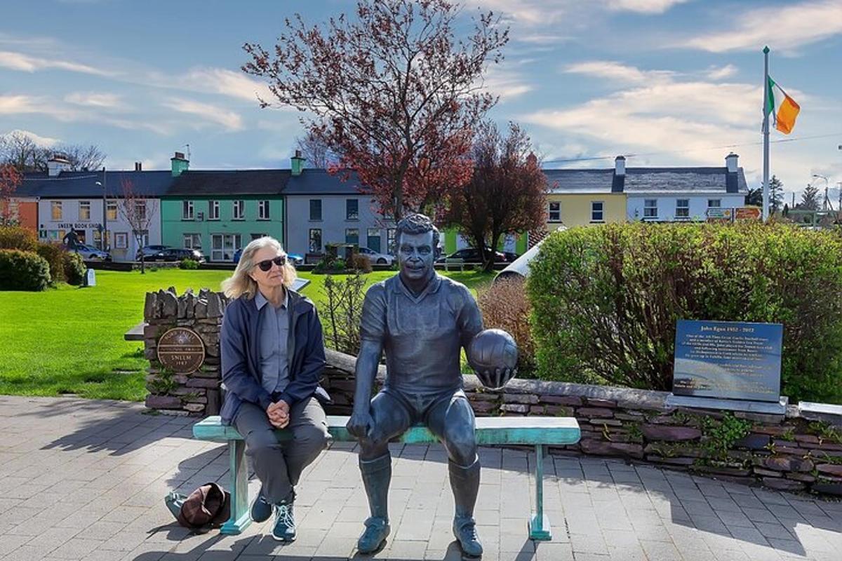 en kvinne som sitter på en benk ved siden av en statue