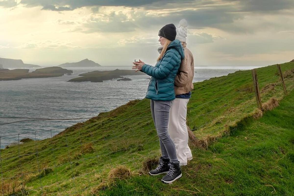 Un hombre y una mujer de pie en una colina con vistas al océano.