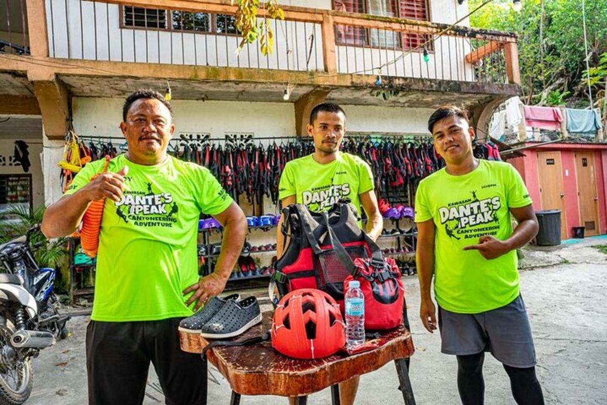 tre uomini in camicia verde in piedi accanto a un tavolo con un casco