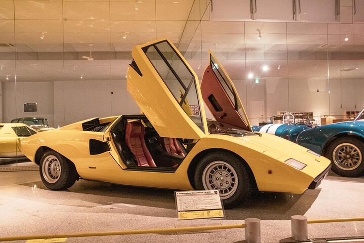 a yellow car with its hood open in a museum