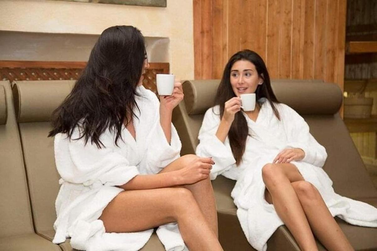 dve ženski, ki sedita v brisačah in držita skodelici kave