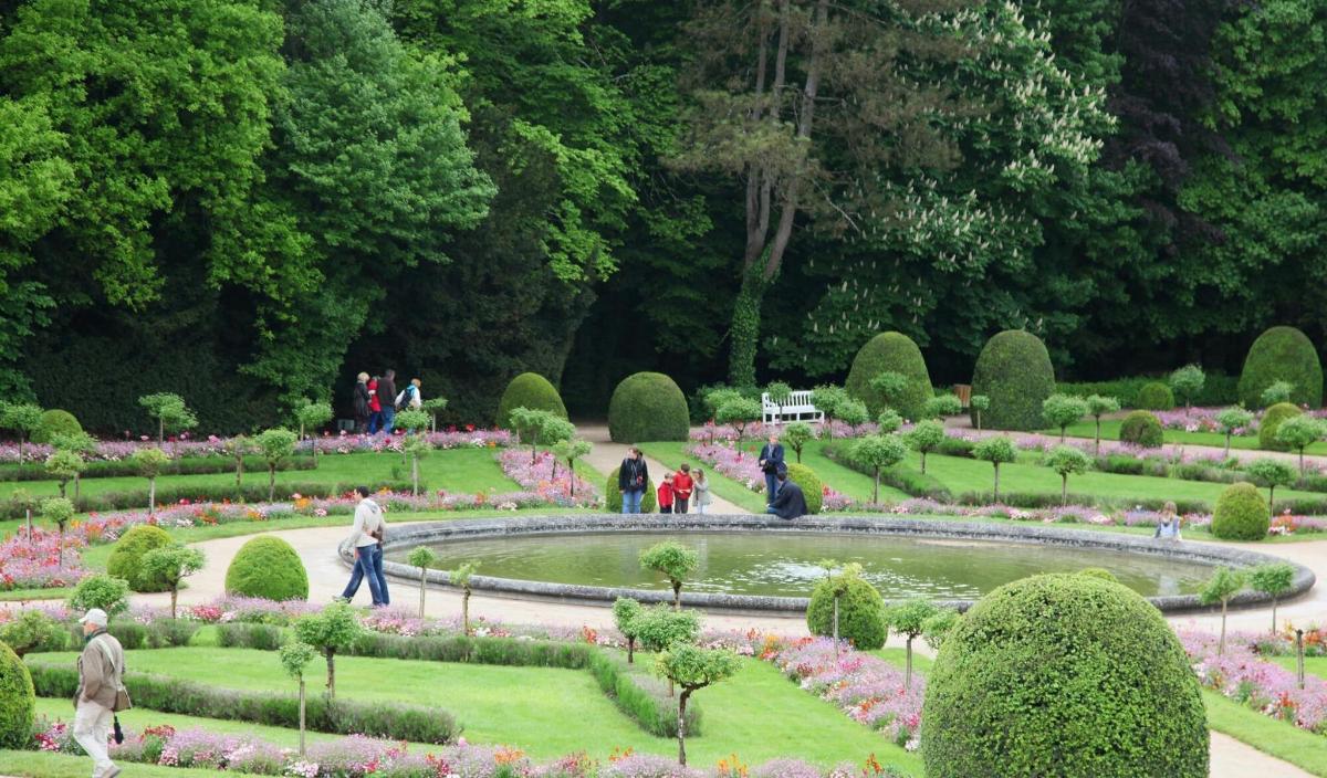 a garden with a fountain and people walking around it
