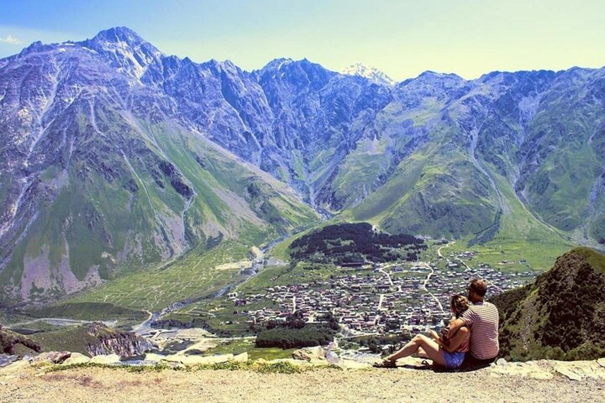 two people sitting on top of a mountain overlooking a city