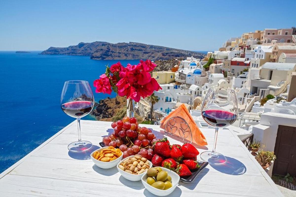Una mesa con dos copas de vino y aperitivos en un acantilado.
