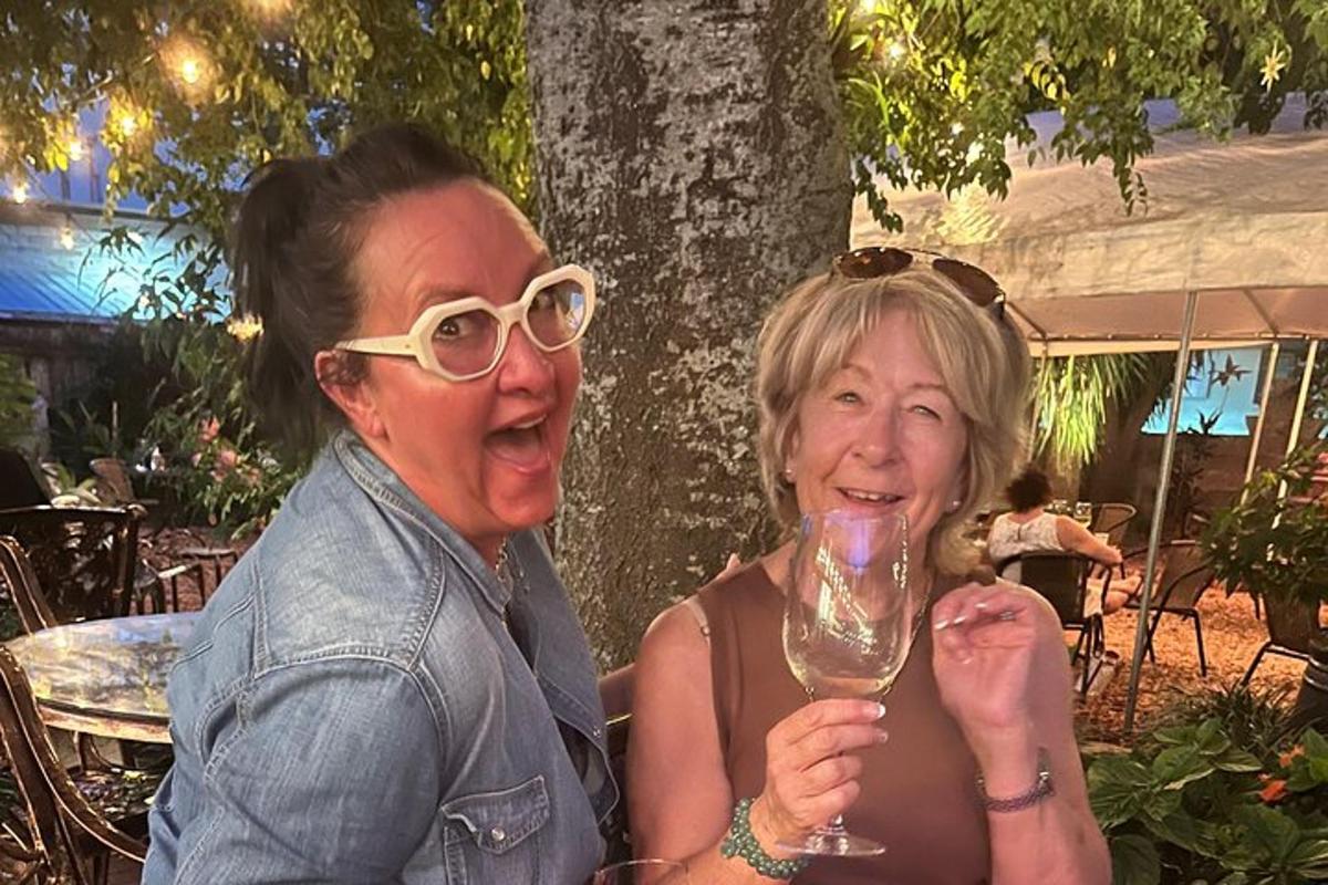 two women sitting next to each other holding a wine glass