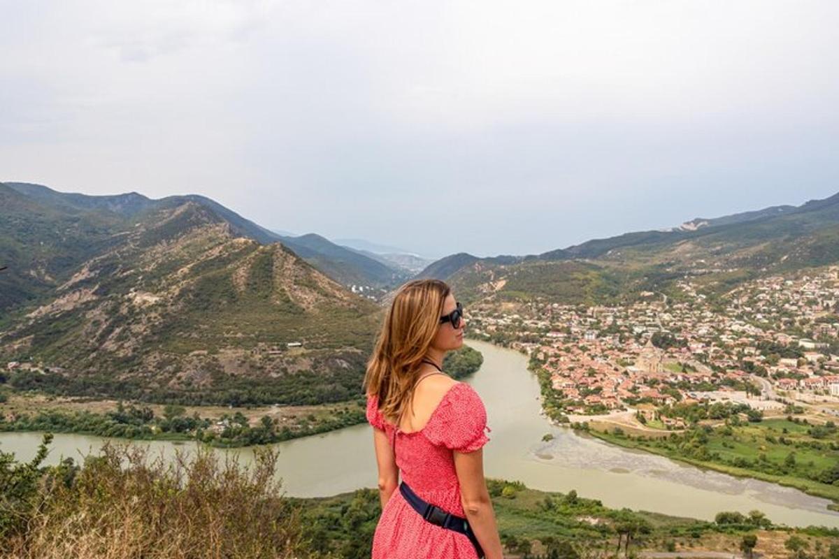 a woman standing on top of a hill overlooking a river