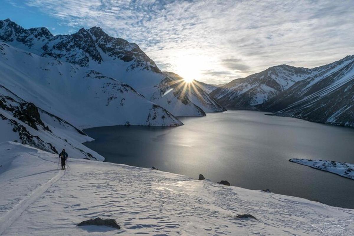 Una persona esquiando en una montaña cubierta de nieve con un lago.