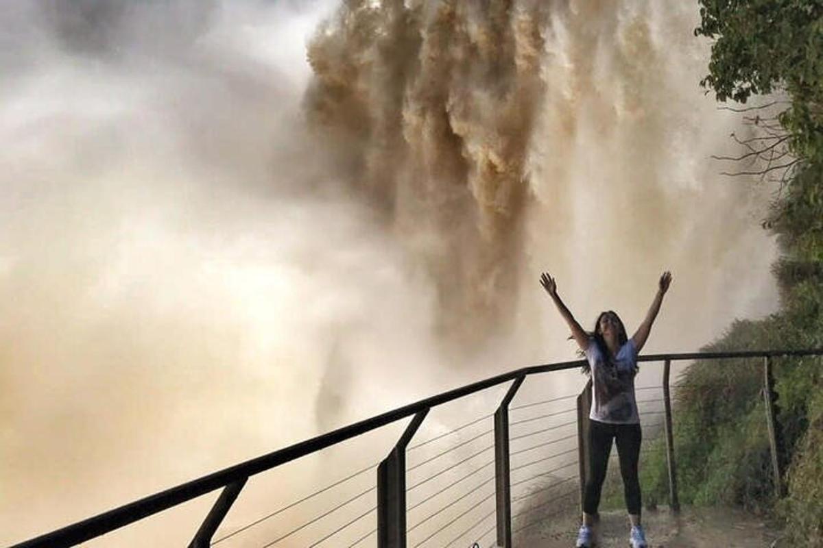 uma mulher em pé em uma ponte com as mãos no ar