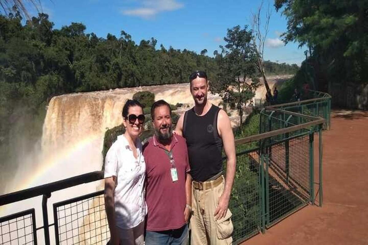 três homens em pé em frente a uma cachoeira