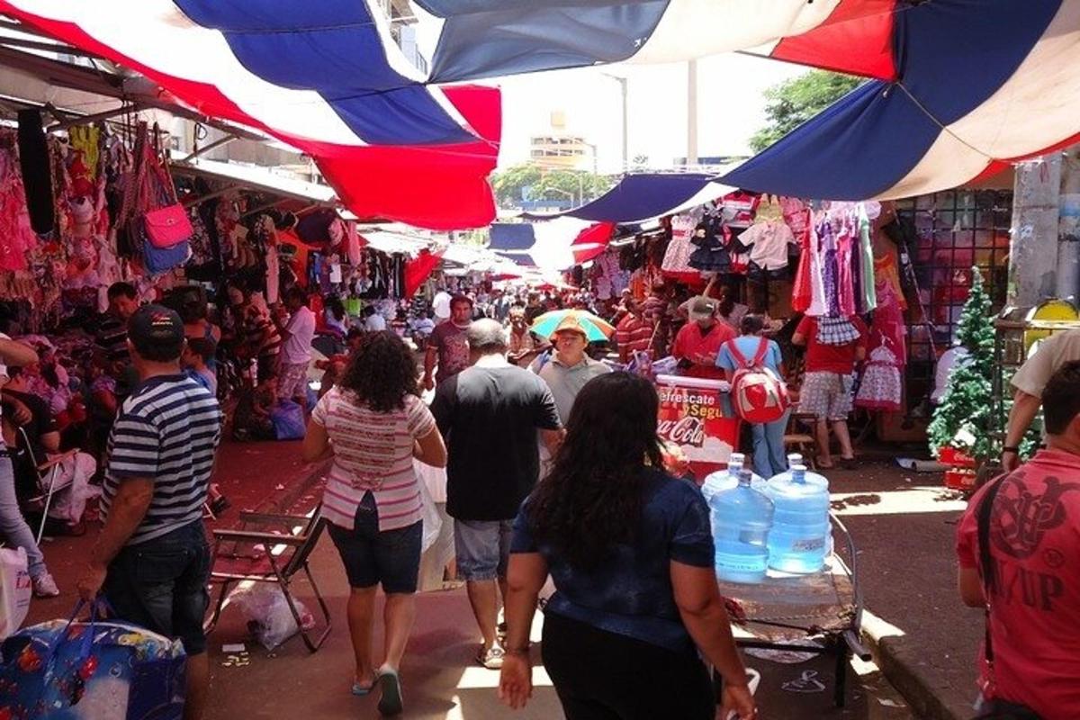 um grupo de pessoas caminhando por um mercado com guarda-chuvas