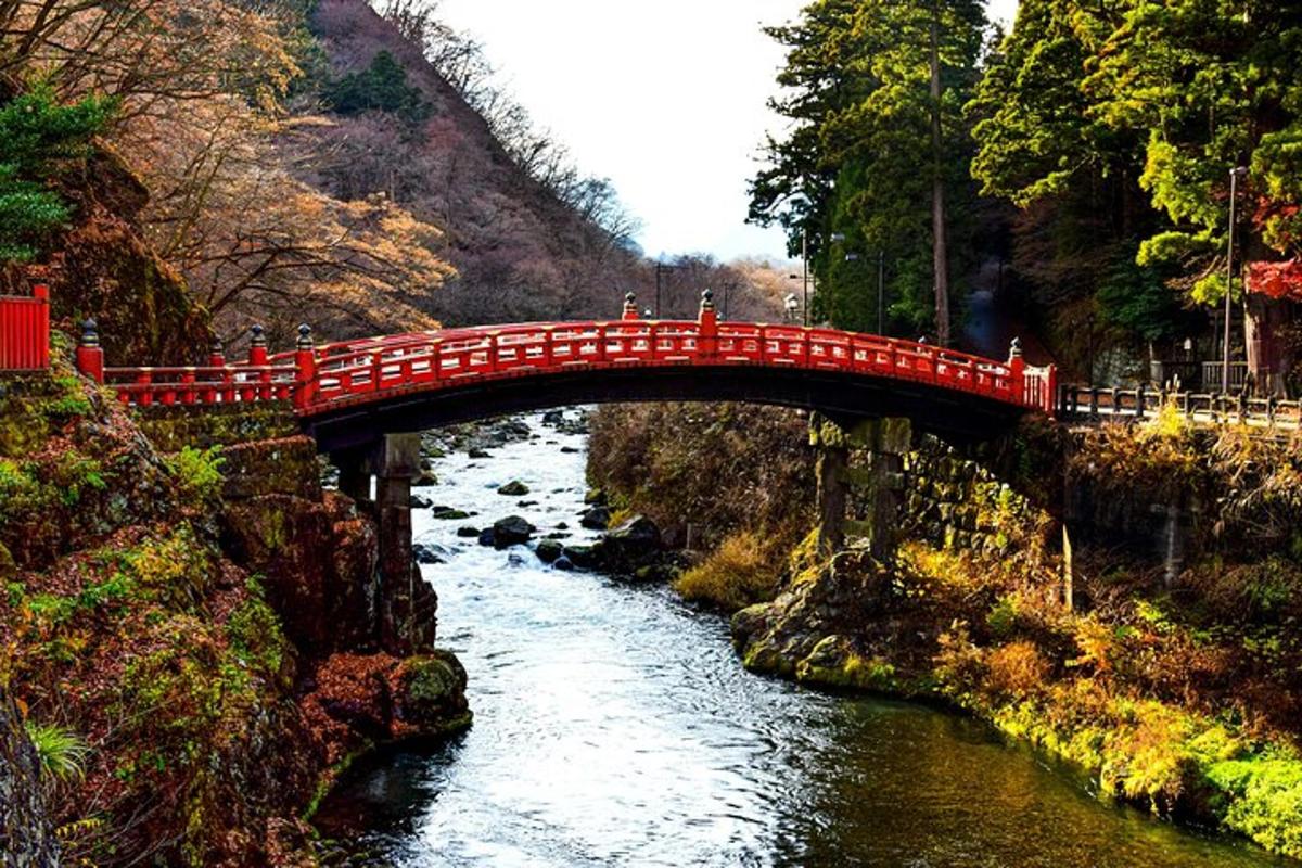 Un puente rojo sobre un río con gente en él.