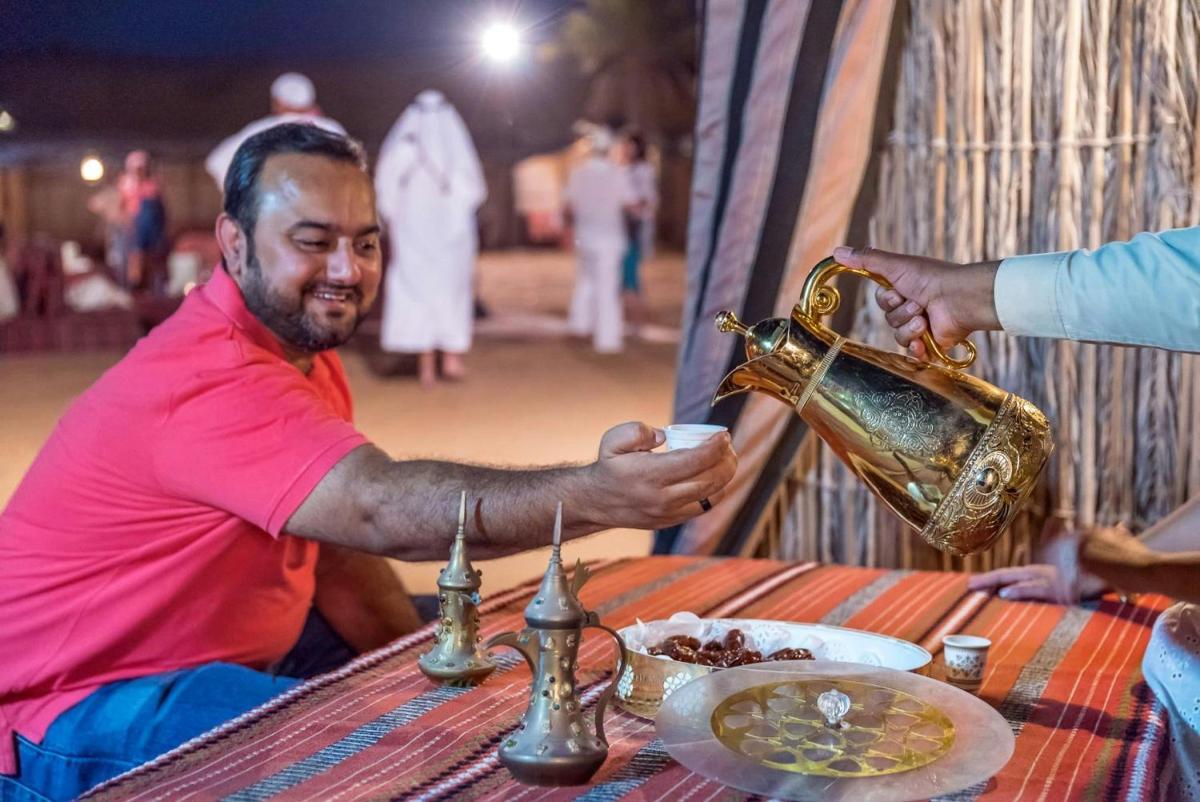 a man sitting at a table with a tea kettle