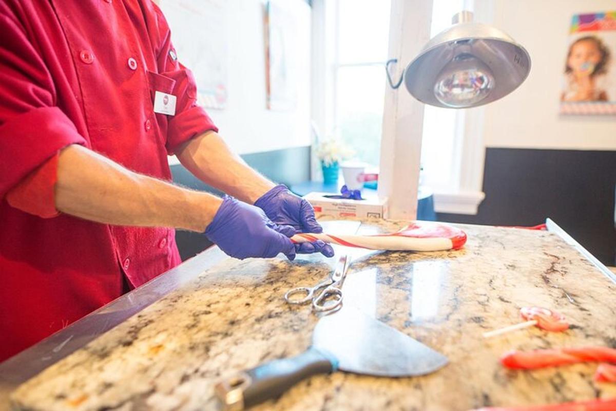 a man cutting a hot dog with scissors on a table