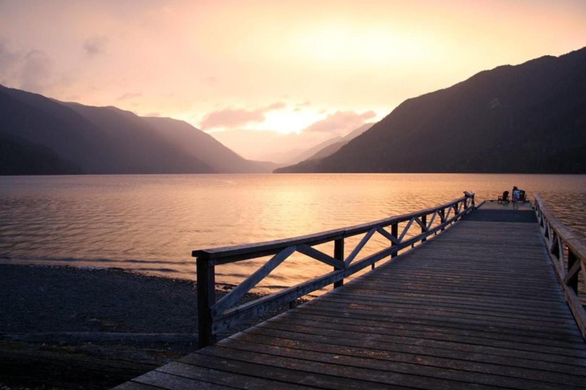 people standing on a wooden bridge over a lake
