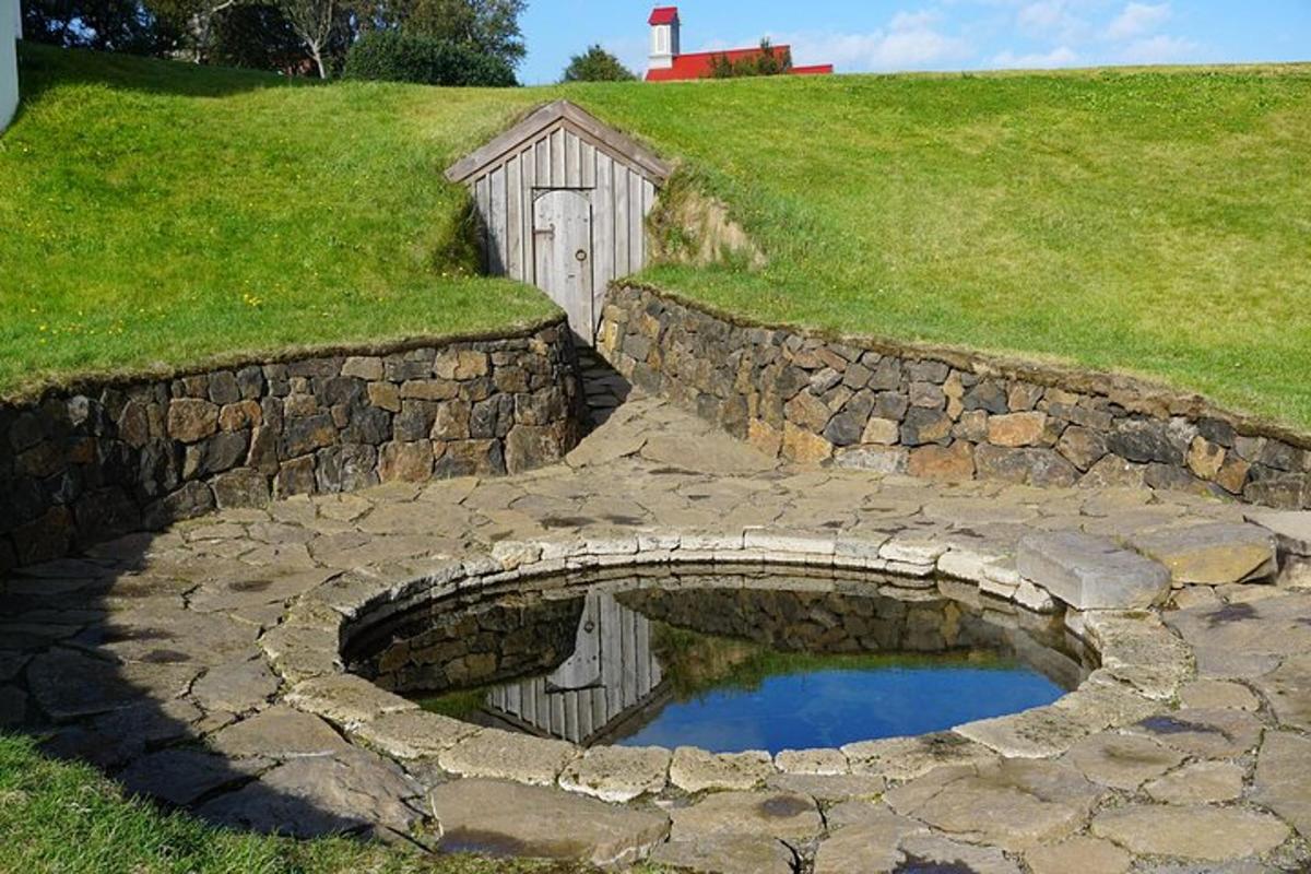 a stone wall with a small pond in front of a barn