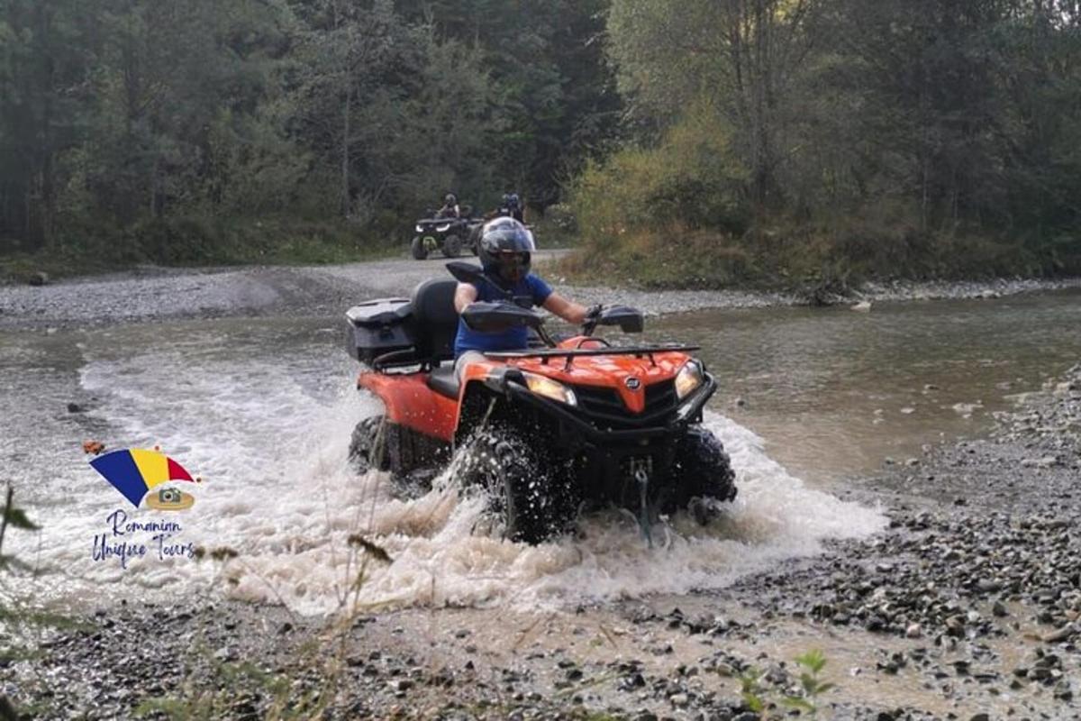o persoană care merge cu un ATV printr-un râu