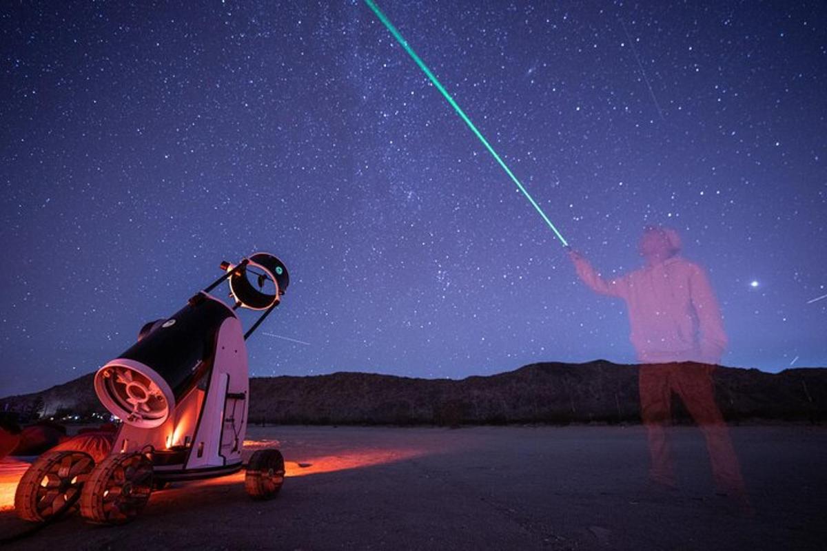 a man standing next to a starry sky with a green lightsaber