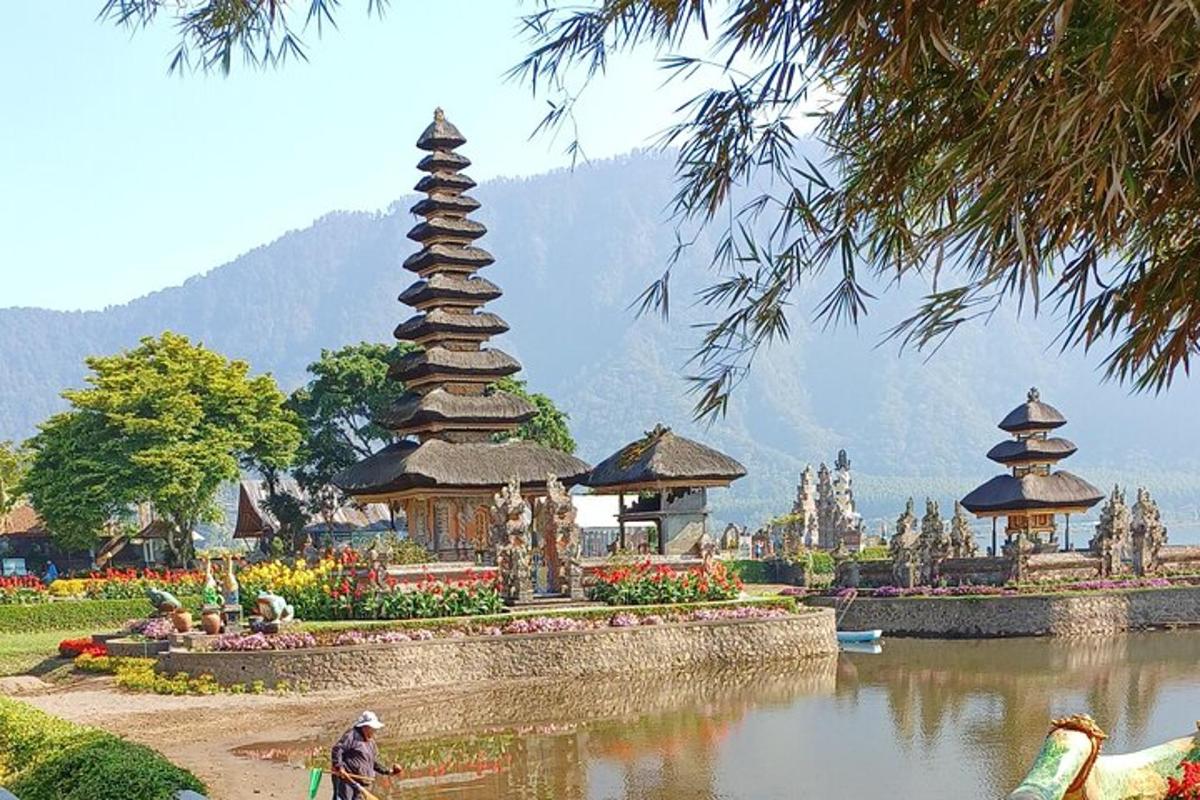 Un hombre montando en bicicleta frente a un lago con pagoda.
