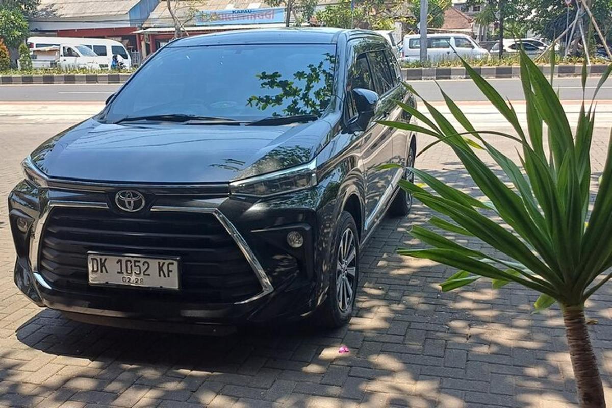 un'auto nera parcheggiata accanto a una palma