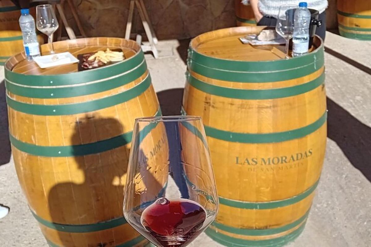 un pahar de vin lângă două butoaie de vin