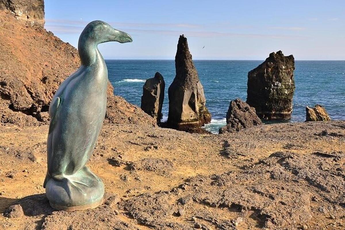 una statua di un uccello seduto su una spiaggia