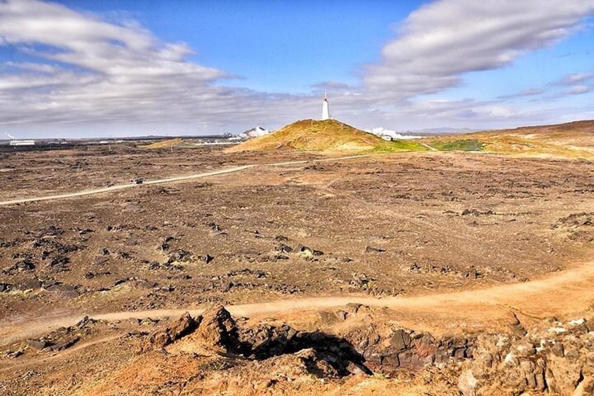un campo sterrato con un faro in cima a una collina