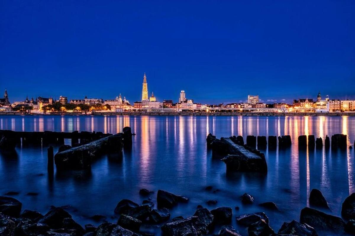 a city skyline at night with rocks in the water