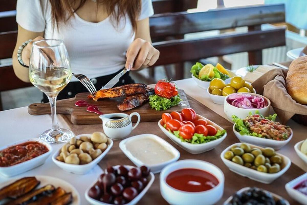a woman sitting at a table with food and wine