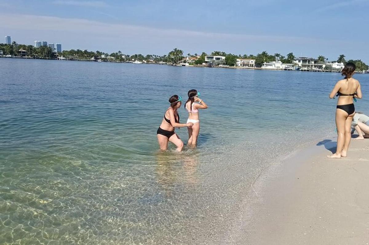 tatlong babaeng naka-bathing suit na nakatayo sa tubig sa isang dalampasigan