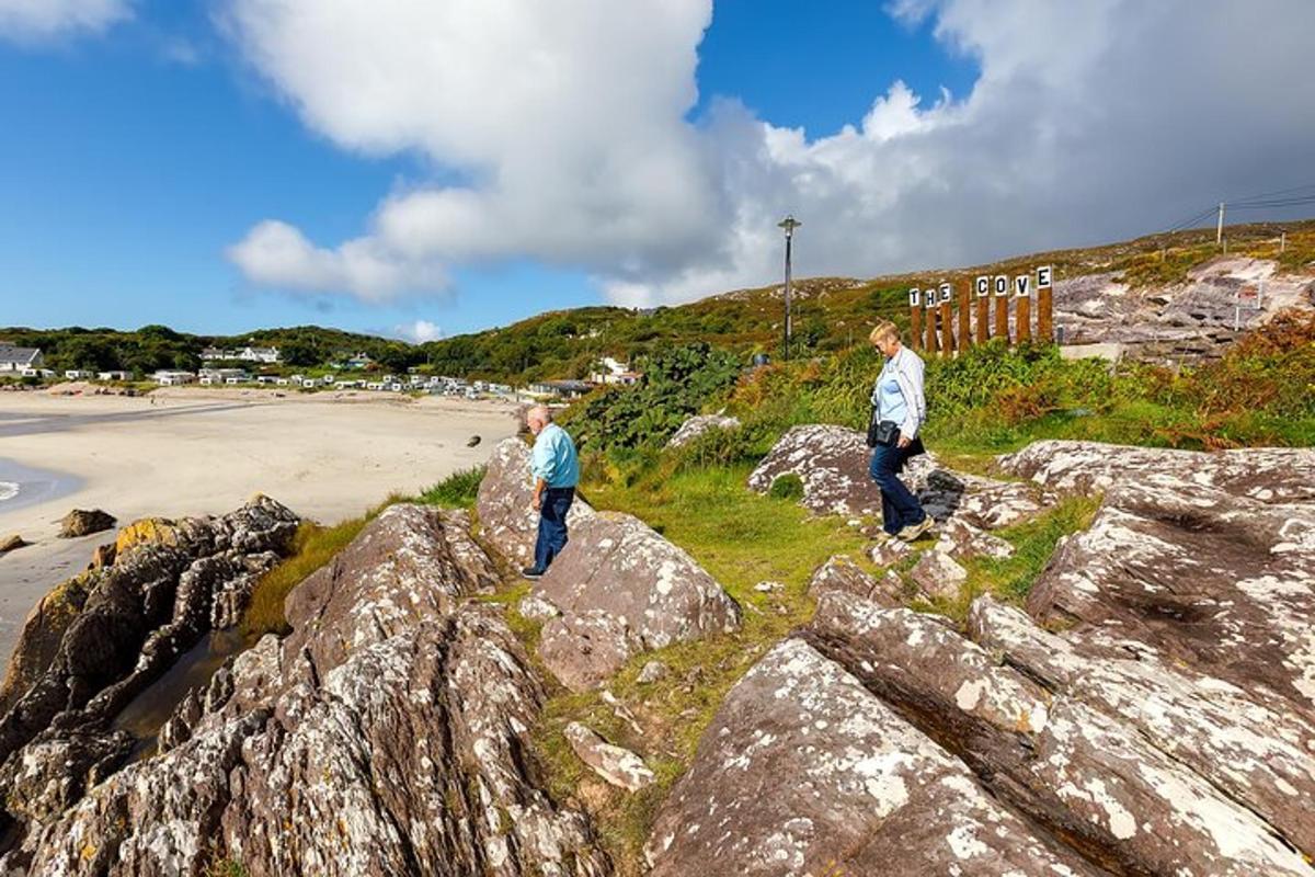 Dos hombres caminan sobre rocas cerca de una playa.