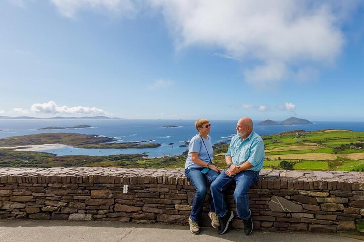 two men sitting on a stone wall overlooking the ocean