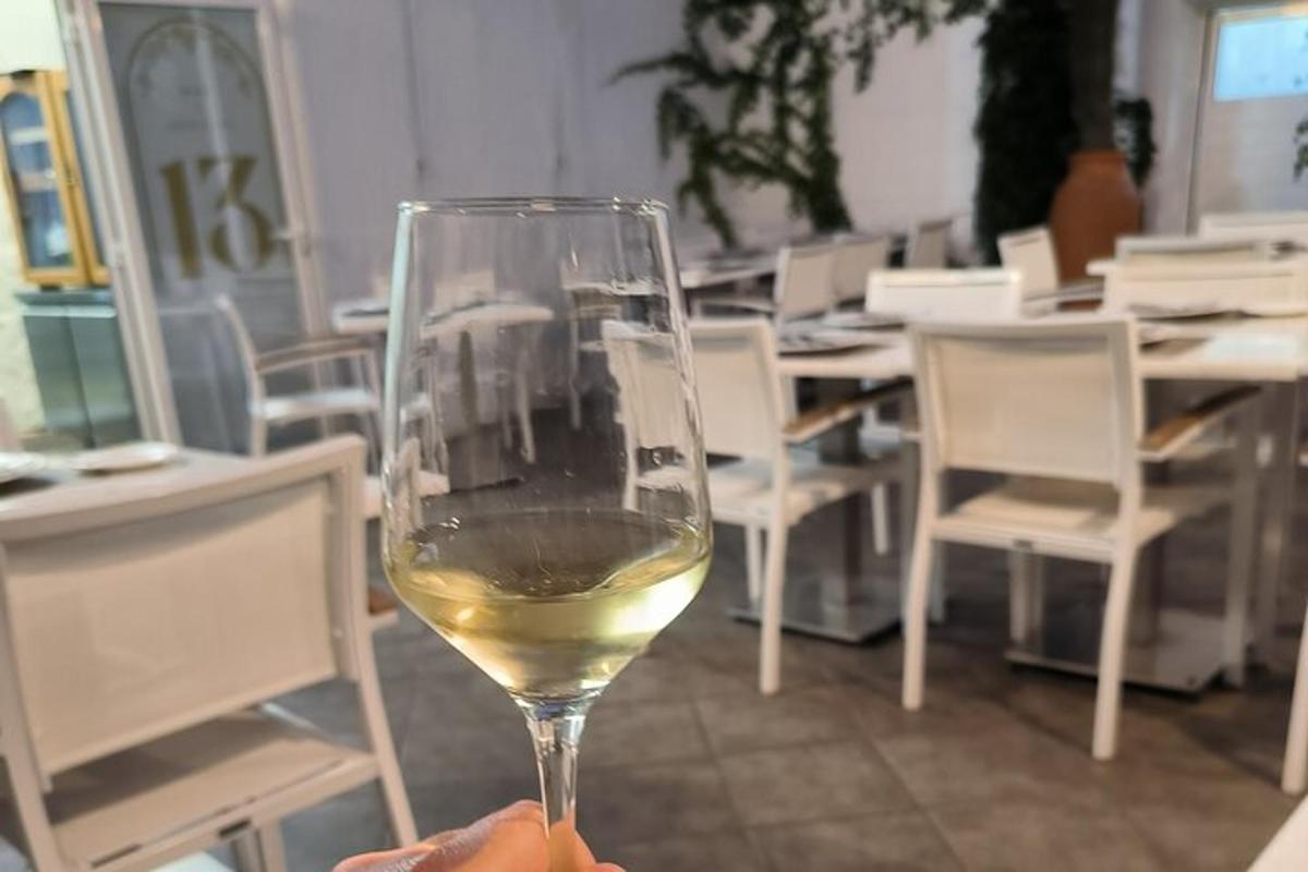 cilvēks, kurš tur rokās glāzi baltvīna