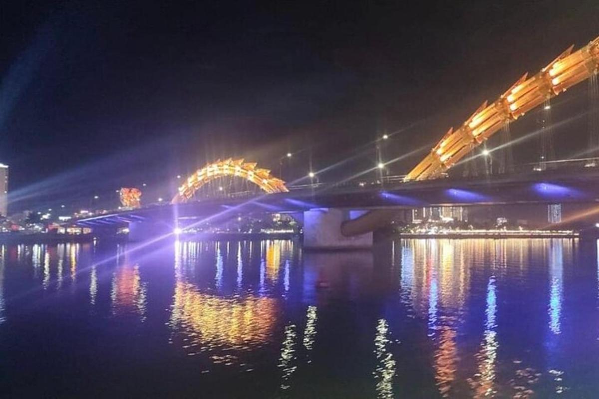 un pont sur une rivière la nuit avec des lumières