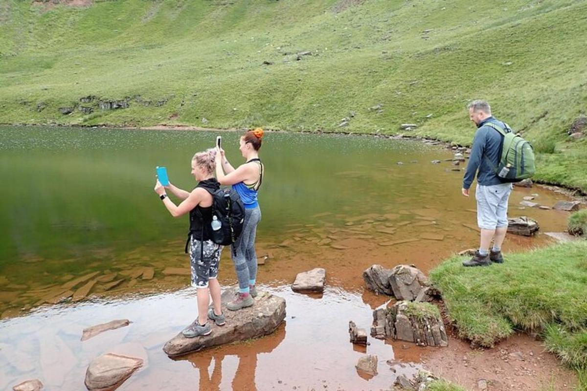 en gruppe mennesker som står på steiner nær en innsjø