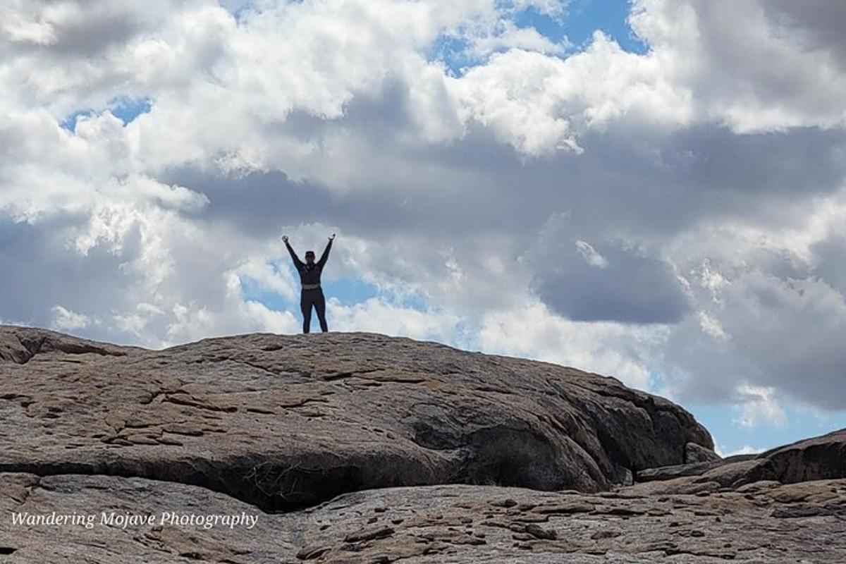 un uomo in piedi su una roccia con le mani in aria