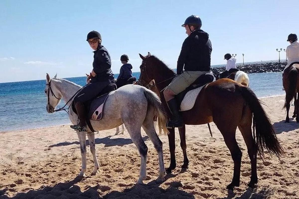 en gruppe mennesker som rir på hester på stranden